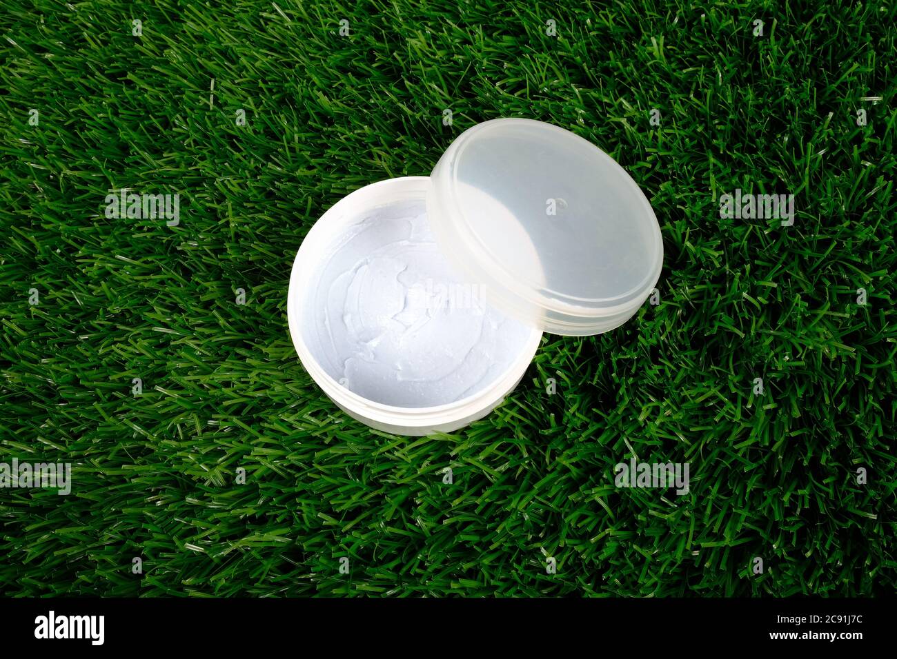 beauty, white jar with body scrub on green grass background close-up. skin care cosmetics. Stock Photo