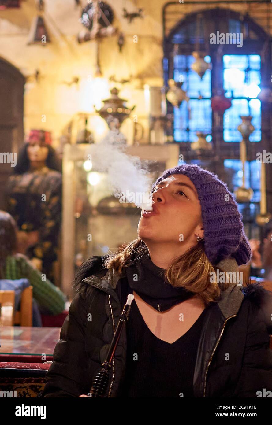 Vertical shot of a young blonde female smoking in the bar Stock Photo