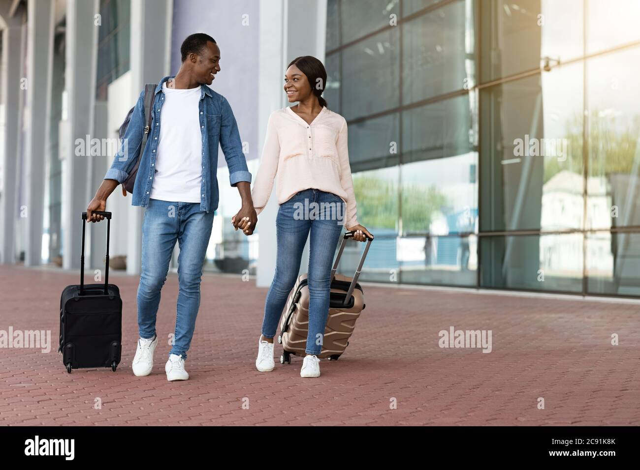 Ready for travel. Happy black couple walking with luggage near airport ...
