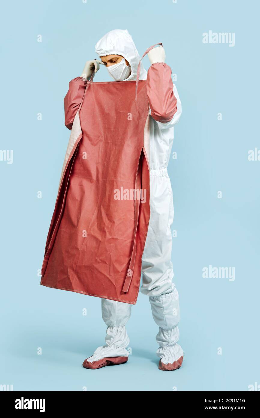 Serious looking sergeon in a white gown putting on red leather apron Stock Photo Alamy