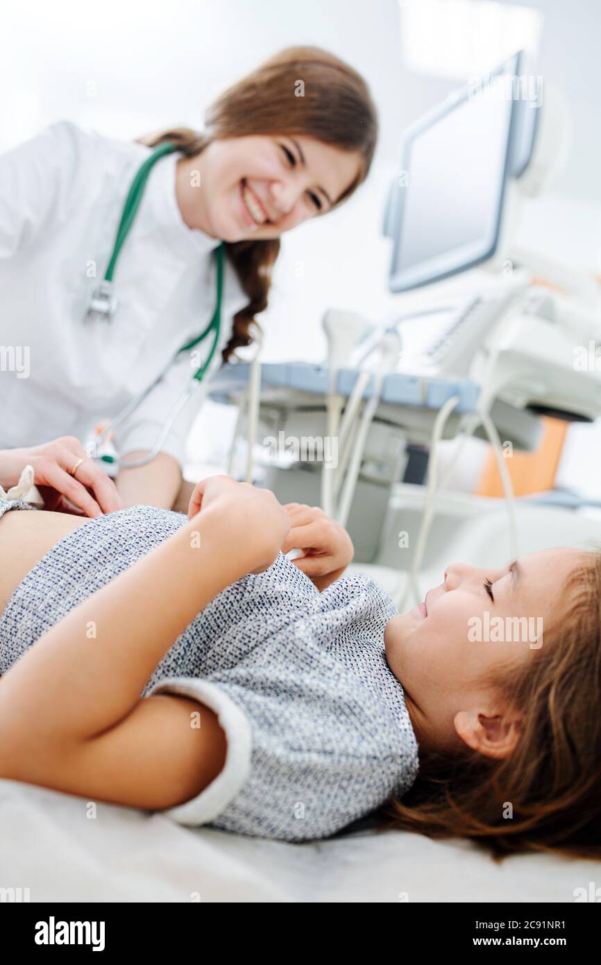 Chatty female doctor pressing her fingers against stomach of a little girl Stock Photo