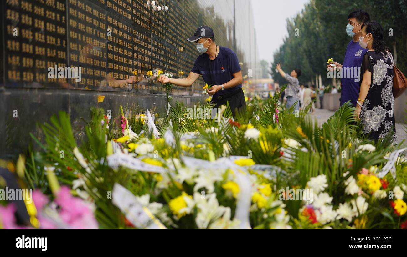 Tangshan. 28th July, 2020. People mourn for the deceased in the 1976 Tangshan Earthquake in front of a memorial wall in Tangshan, north China's Hebei Province, July 28, 2020, the 44th anniversary of the earthquake. Credit: Dong Jun/Xinhua/Alamy Live News Stock Photo