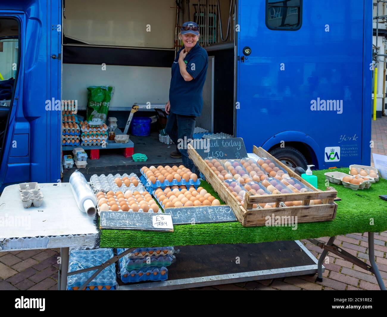 Smiling lady stallholder selling eggs on a specialist farmer's market stall in North Yorkshire Stock Photo