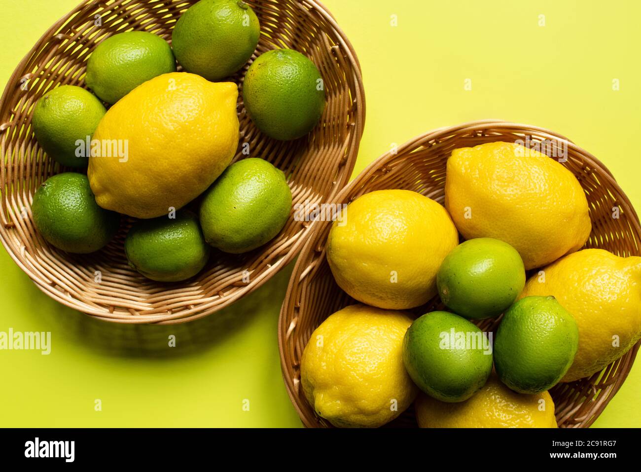 top view of ripe limes and lemons in wicker baskets on colorful ...