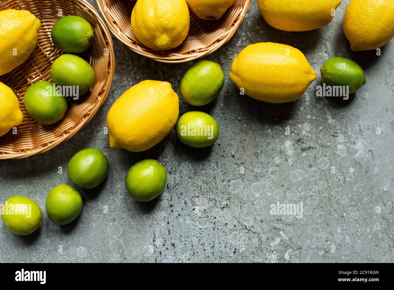 top view of ripe yellow lemons and green limes in wicker baskets on ...