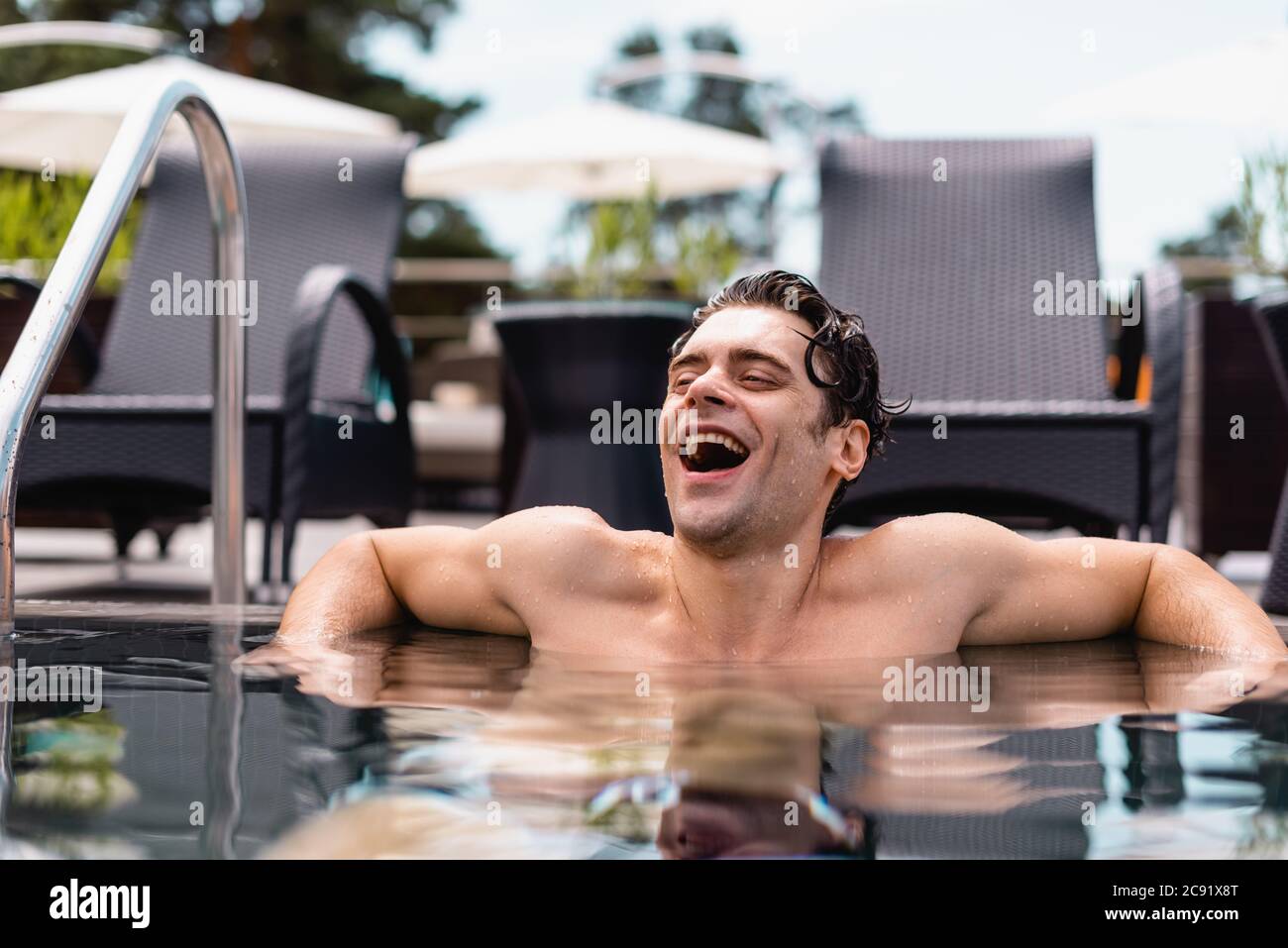 selective focus of excited and wet man laughing in swimming pool Stock ...