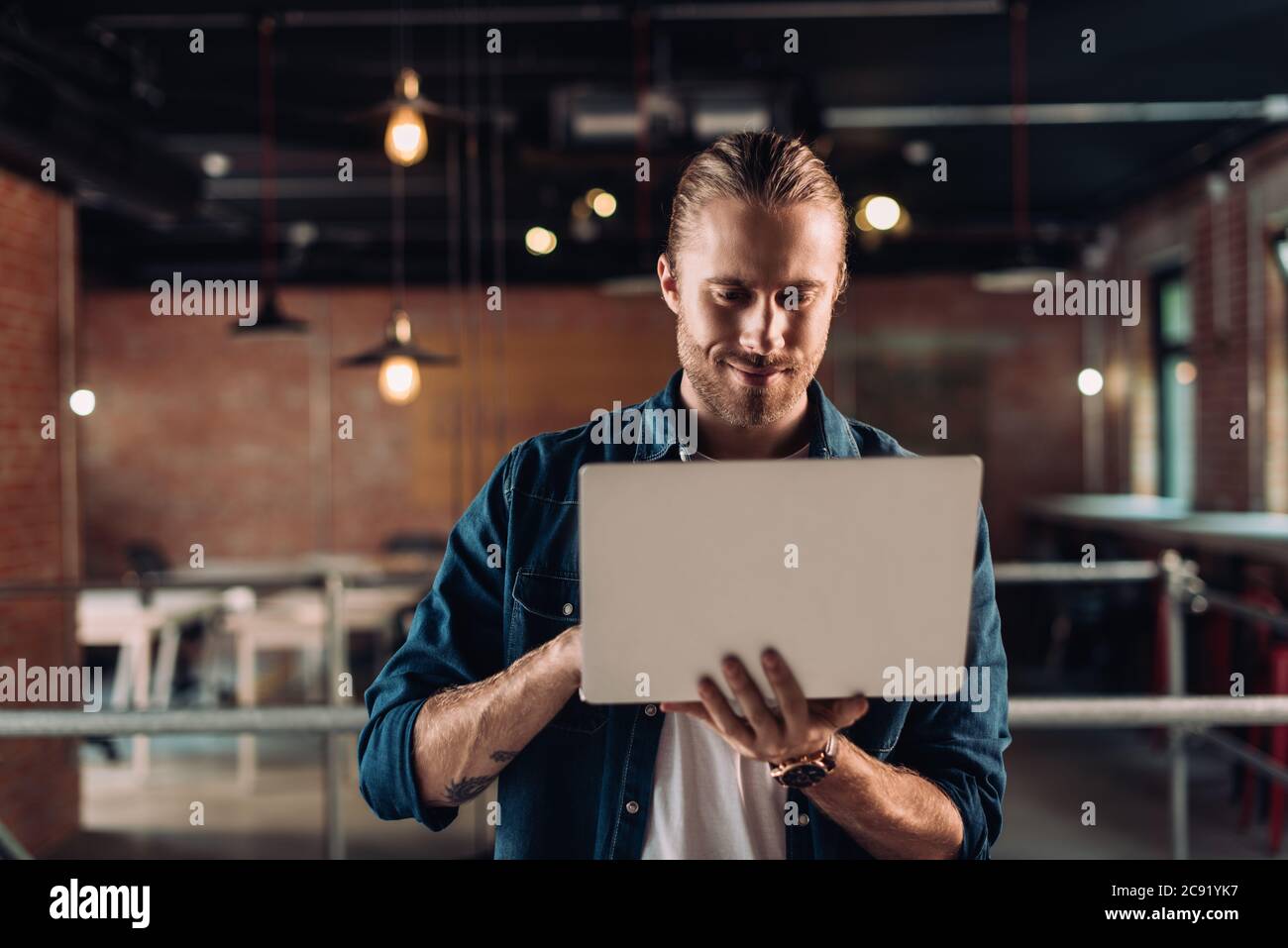 bearded businessman holding and using laptop in modern office Stock Photo