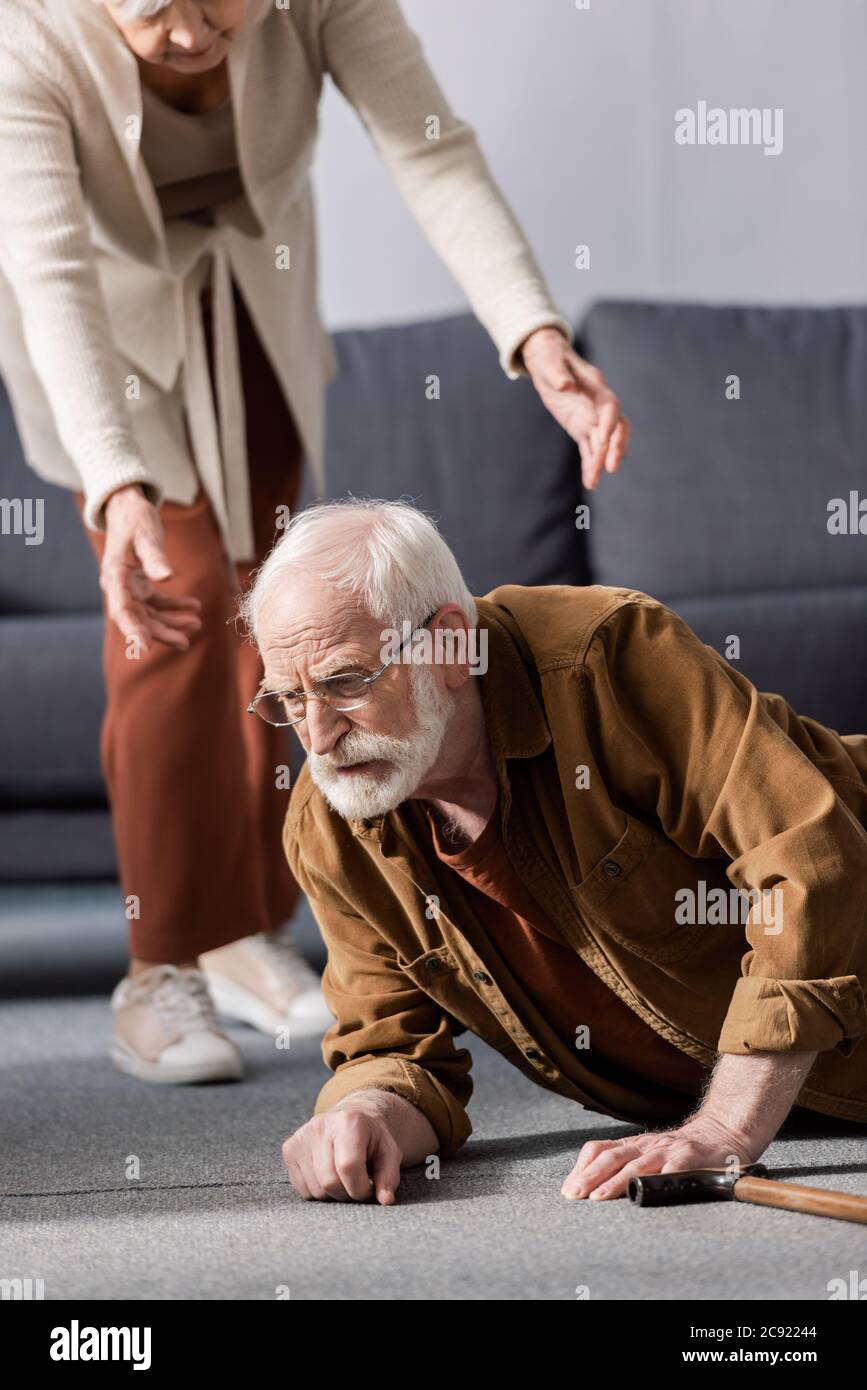 cropped view of woman helping fallen senior husband to get up from