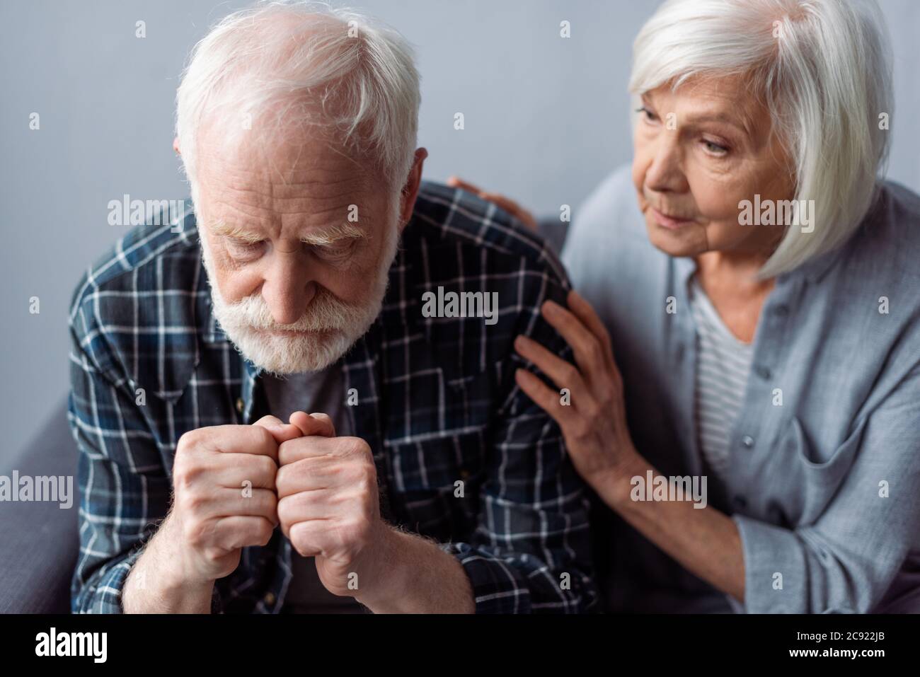 worried senior woman touching husband suffering from dementia and