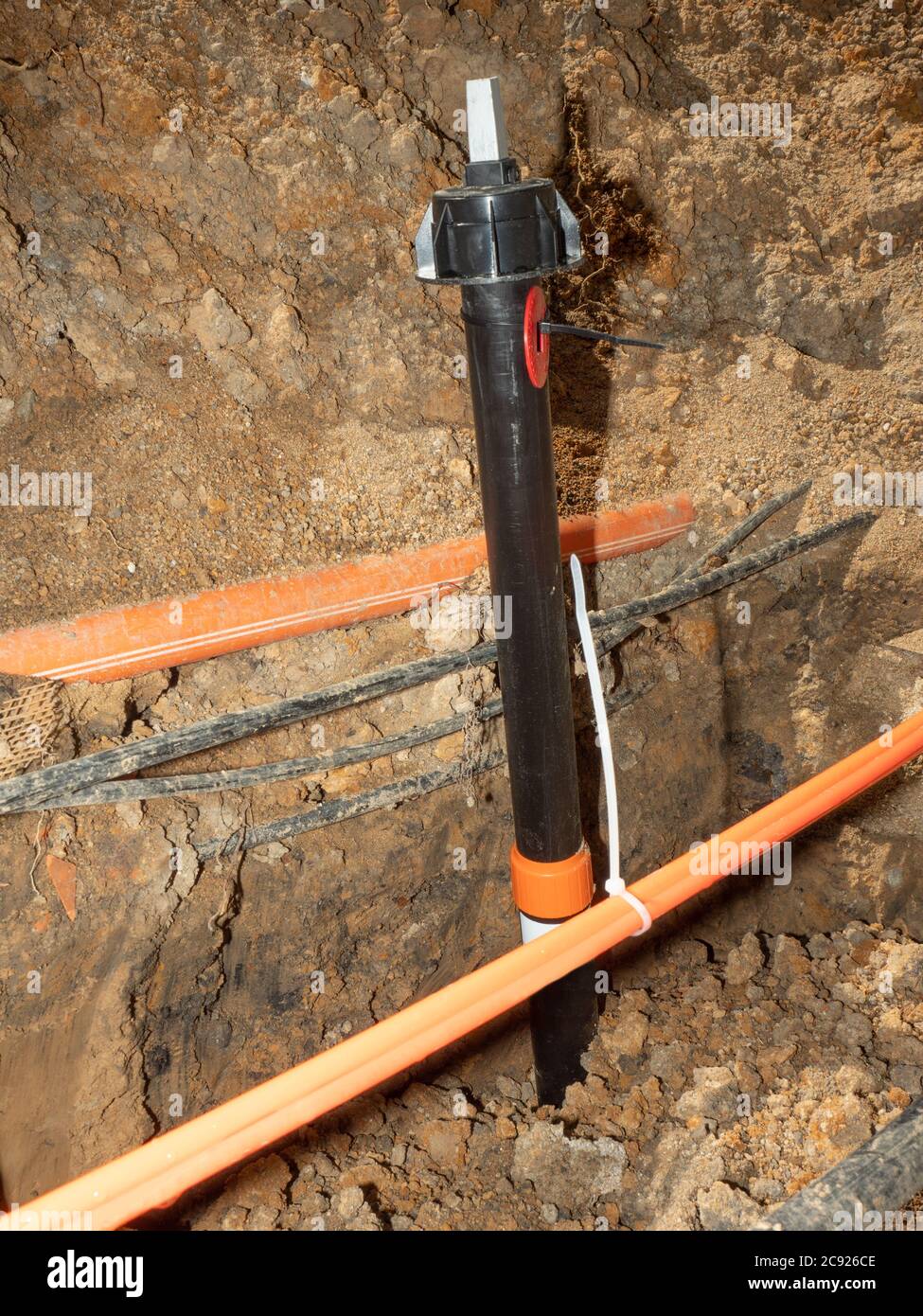 Water supply valve and lines of metallic and fiber optic cables. The trench carries the conduits