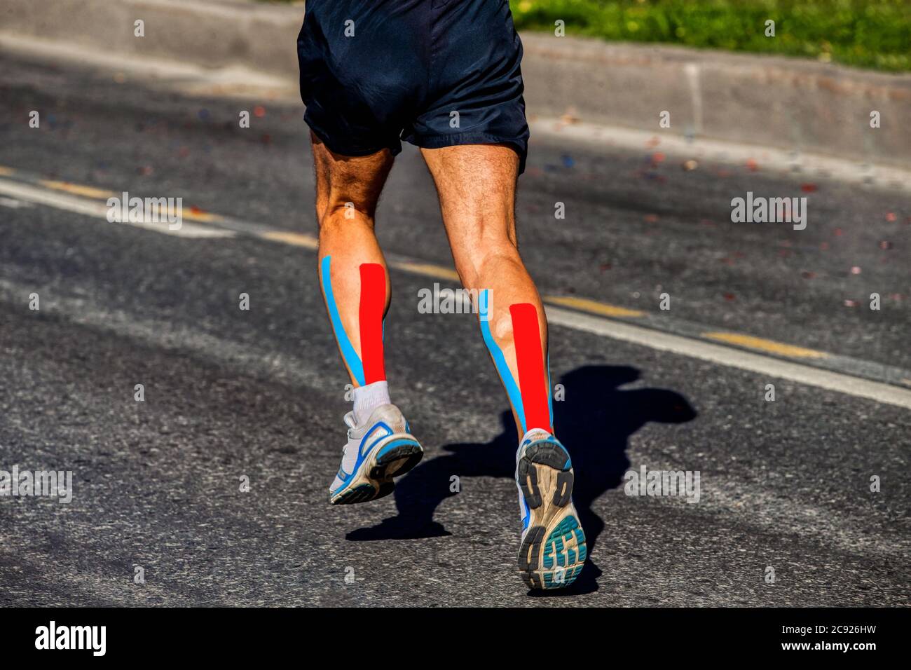 kinesio tapipng on calf muscle of athlete runner running on dark asphalt Stock Photo