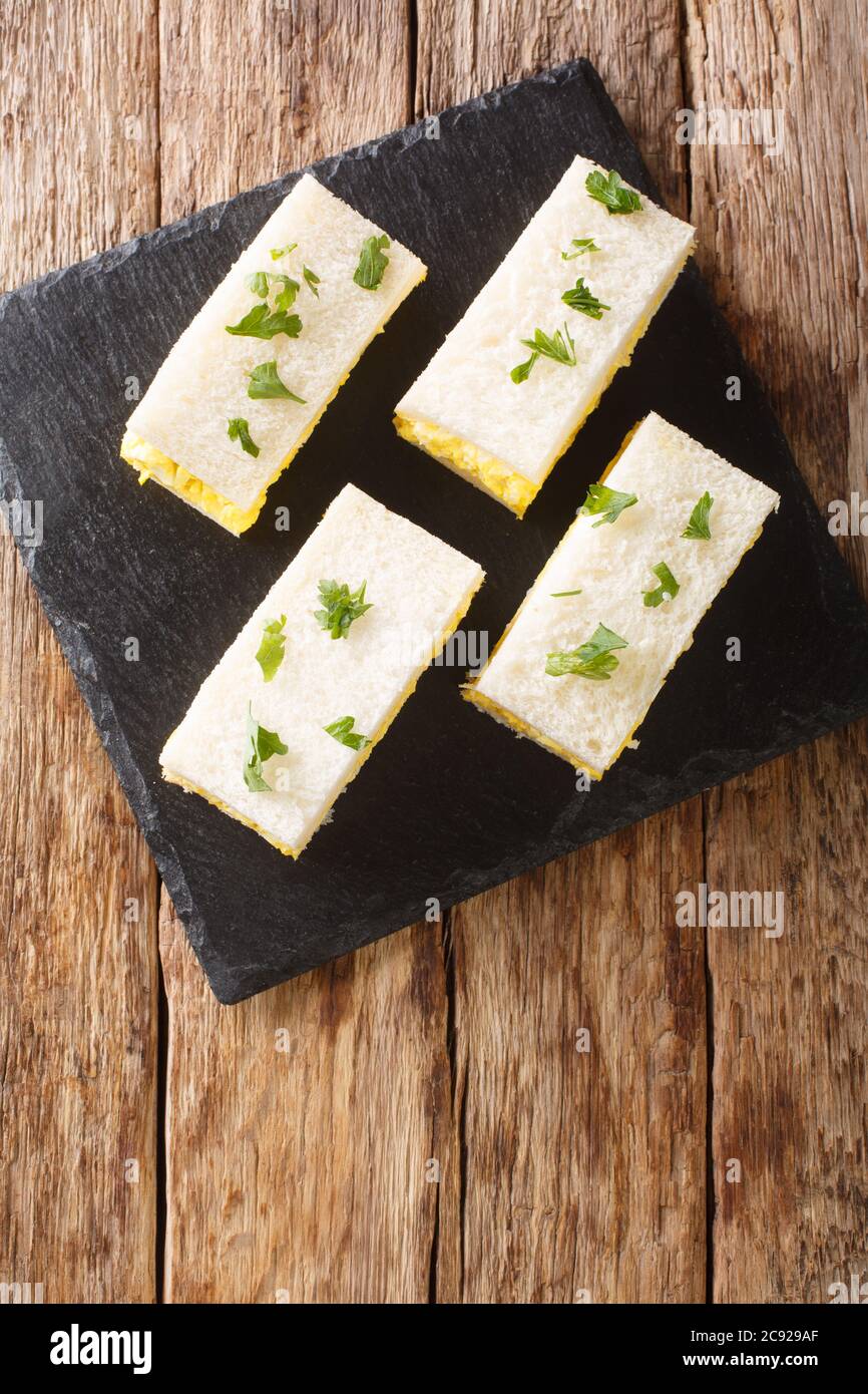 Tamago sando Japanese egg salad sandwich closeup on the board on the table. Vertical top view from above Stock Photo