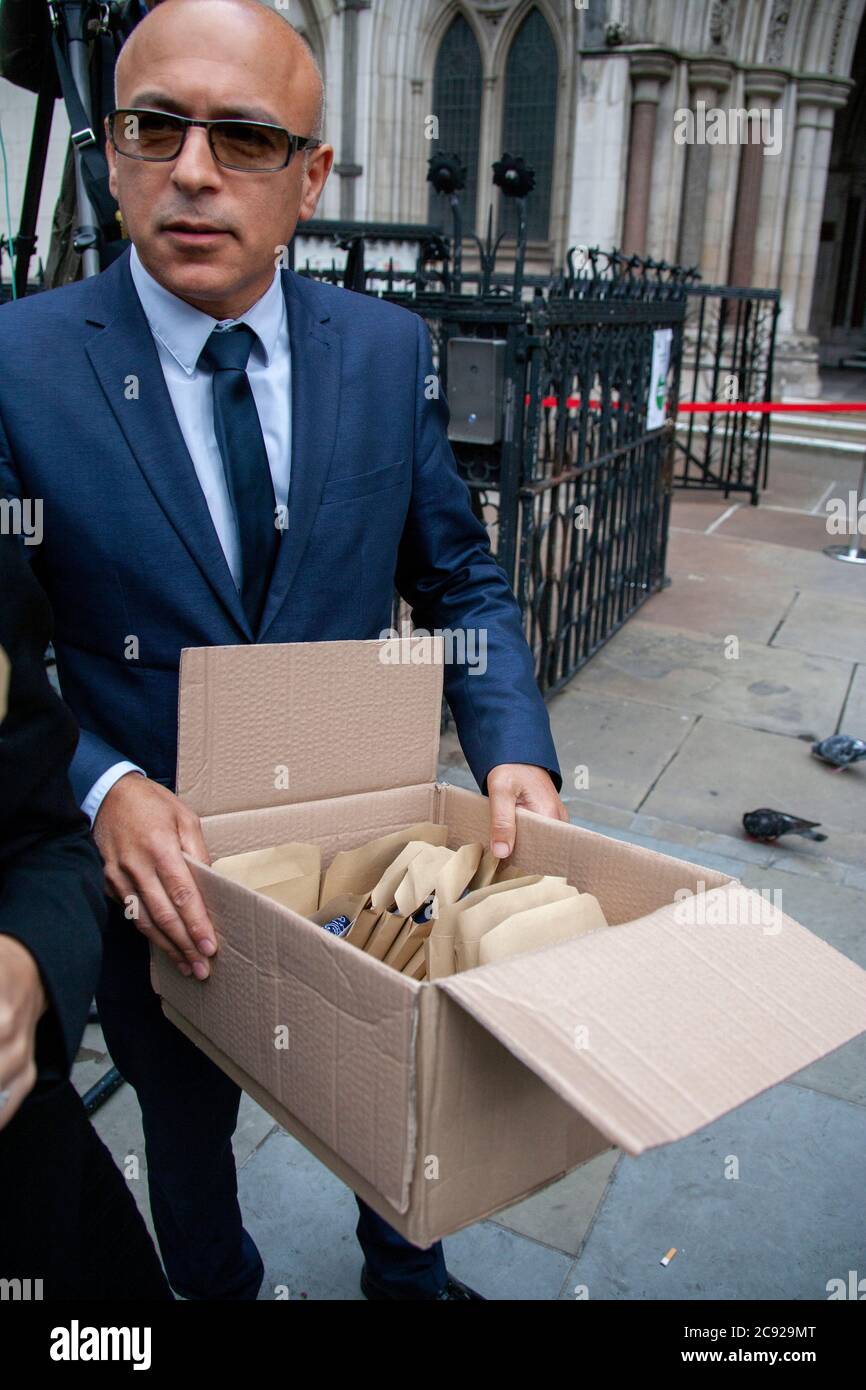 London, UK. 28th July 2020. A member of Johnny Depp’s team holding a boxful of signed souvenirs to distribute amongst his fans on his last day (16) of his libel trial against The Sun's publishers NGN. Credit: Neil Atkinson/Alamy Live News Stock Photo