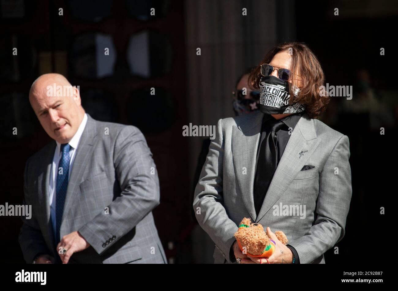 London, UK. 28th July 2020. Hollywood actor and musician, Johnny Depp, arrives at the high court, wearing a face scarf and holding a teddy bear, on day 16 of his libel trial against The Sun's publishers NGN. Credit: Neil Atkinson/Alamy Live News Stock Photo