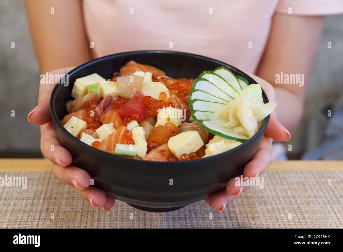 Japanese food. Hand's woman holding rice of Salmon, tuna ,Tekka Don Stock Photo Alamy