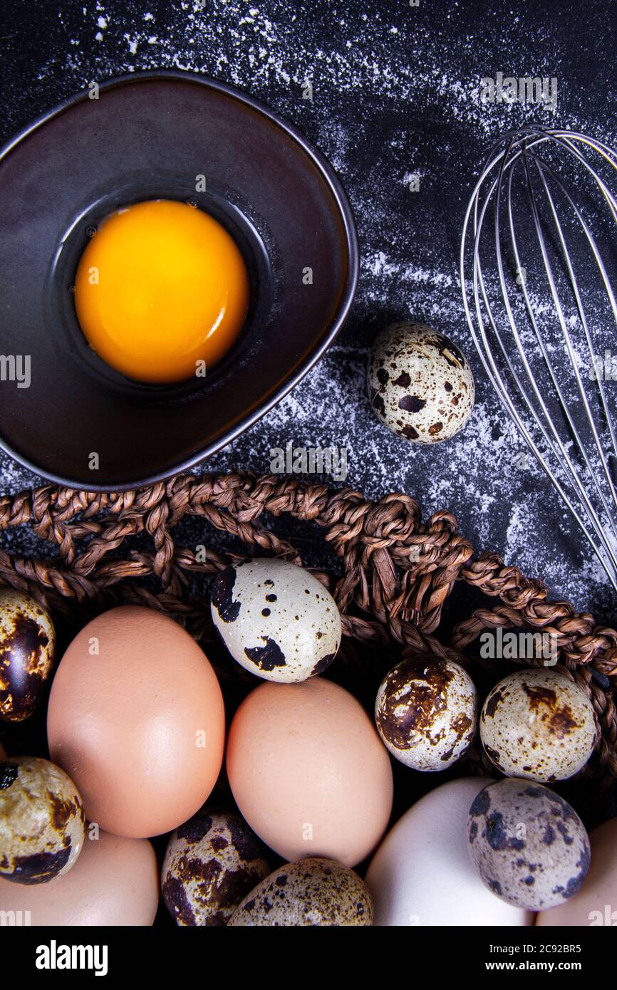 The quail egg is next to the native eggs and an egg yolk outside or
