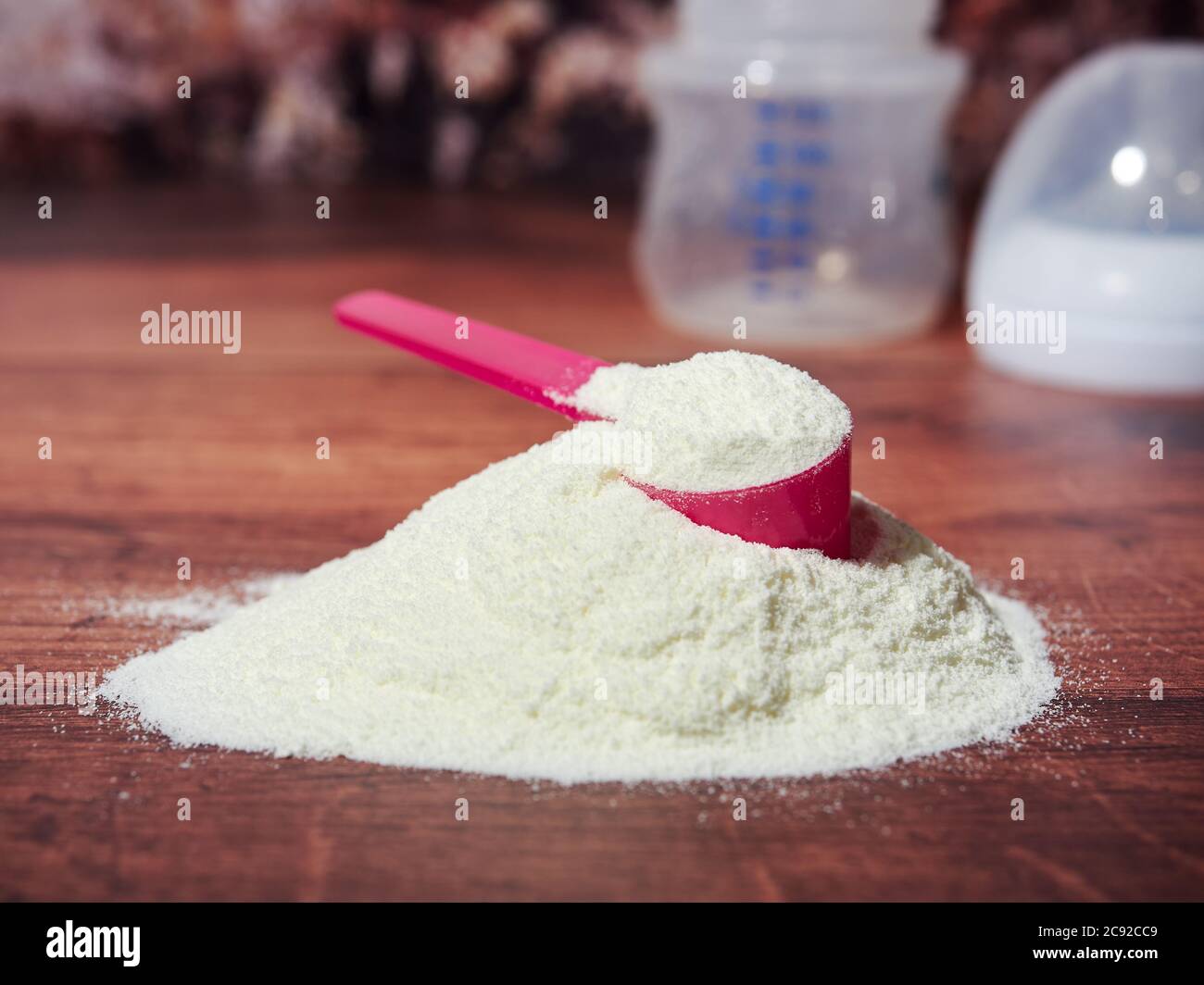A heap of organic milk formula for infants, with measuring spoon, on brown wood background Stock Photo