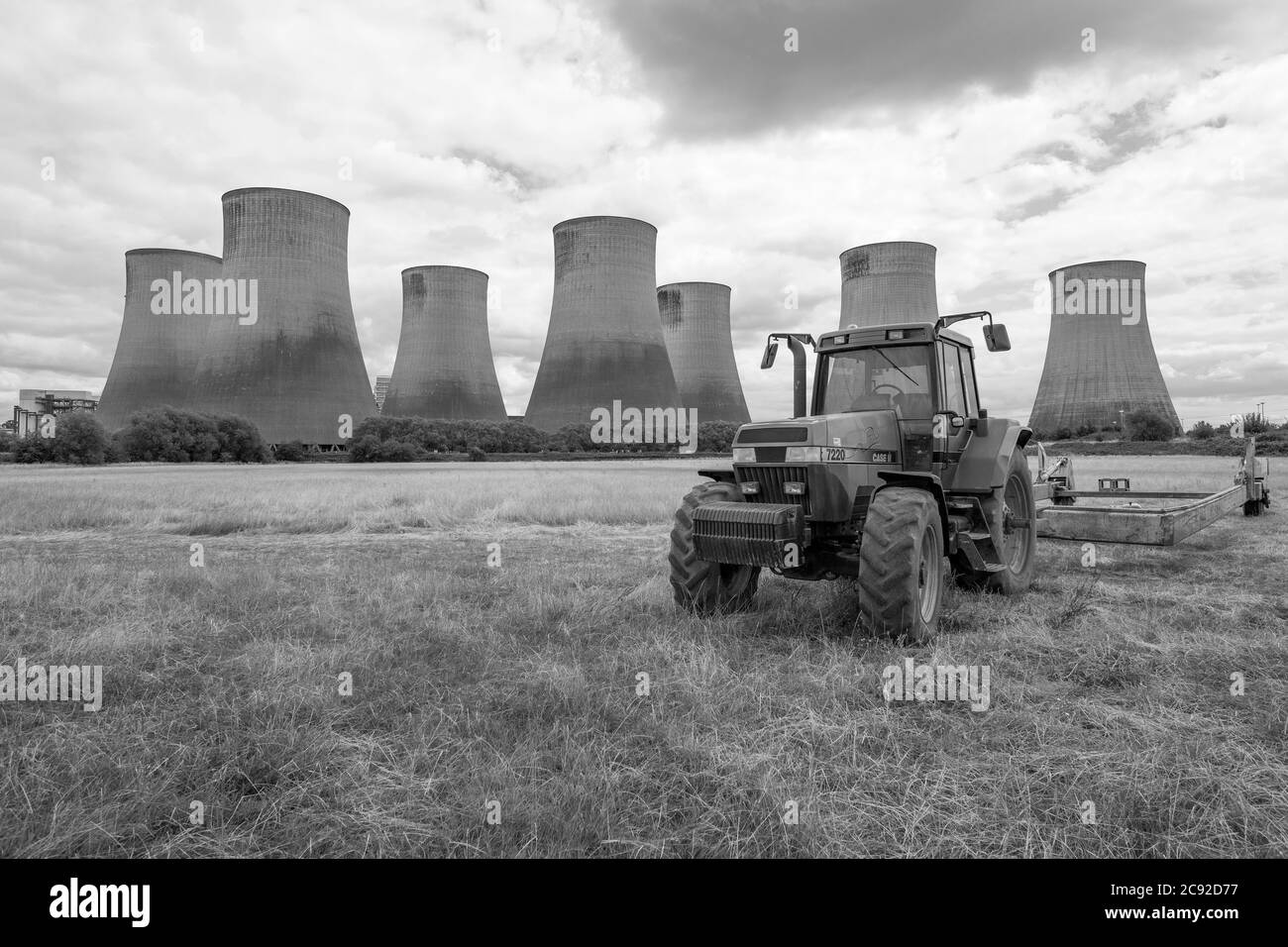 Farm tractor in a field in front of a power station Stock Photo
