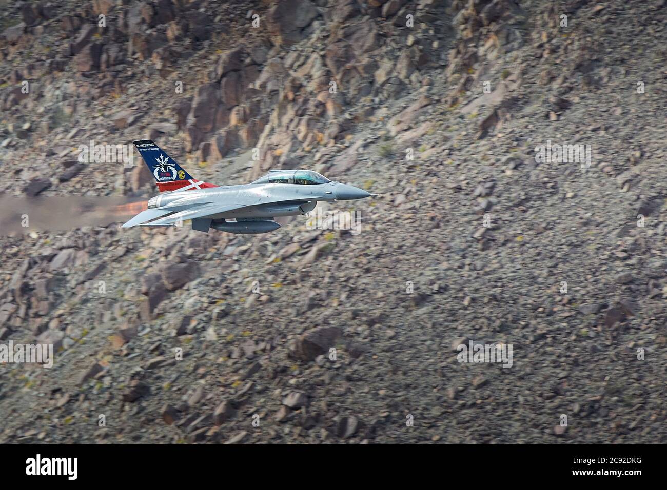 Royal Danish Air Force F-16, With Reheat (Afterburner) Alight, Flying At Low Level And High Speed Though Rainbow Canyon, California, USA. Stock Photo