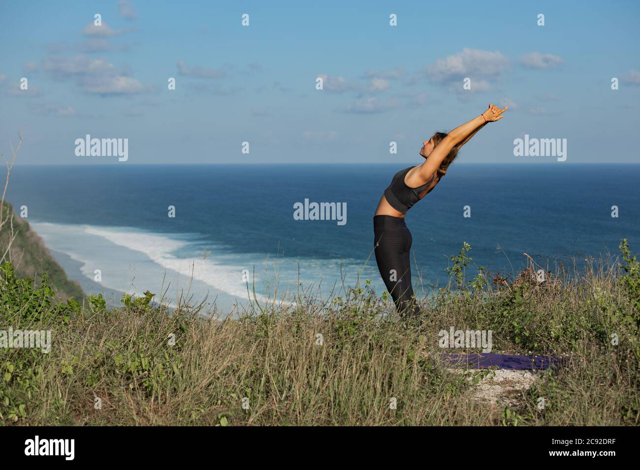 Young woman doing yoga outdoors with amazing back view. Bali. Indonesia. Stock Photo
