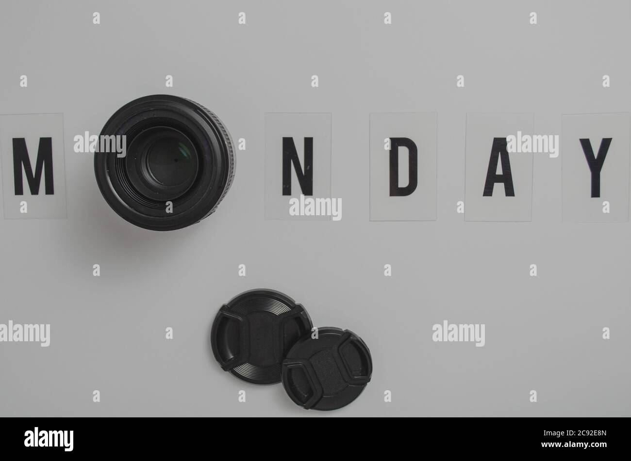 Top view of a white surface with Monday spelling and a camera lens