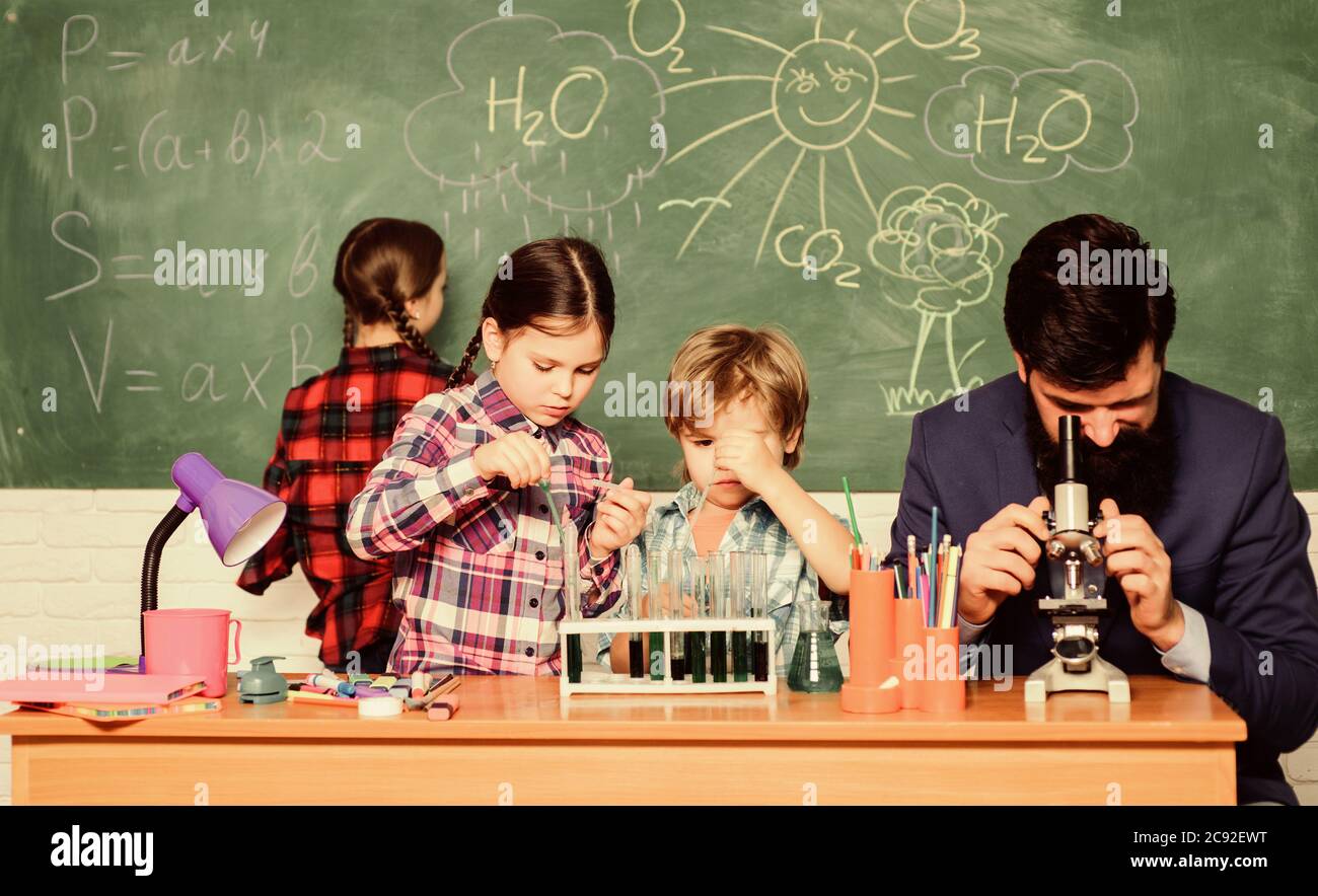 Fascinating chemistry lesson. Man bearded teacher and pupils with test tubes in classroom. Observe reaction. Science is always the solution. School chemistry experiment. Explaining chemistry to kids. Stock Photo