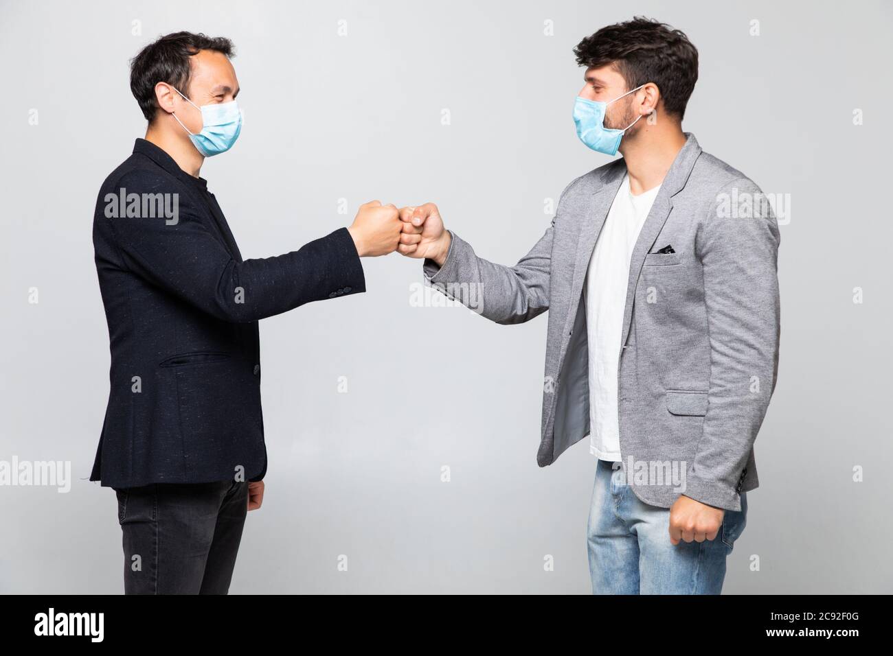 Fist bump greeting. Two people in suits greet each other in a meeting. They give up the untraditional handshake isolated on a white background. Stock Photo