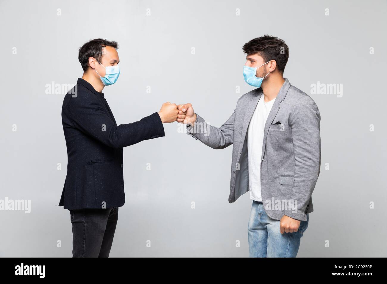 Fist bump greeting. Two people in suits greet each other in a meeting. They give up the untraditional handshake isolated on a white background. Stock Photo