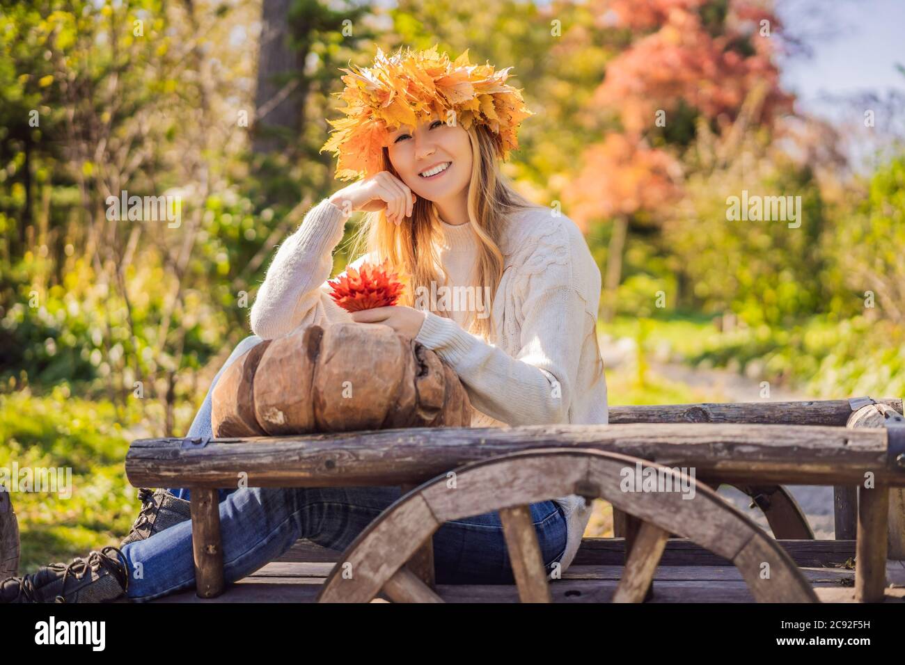 Outdoors lifestyle close up portrait of charming blonde young woman wearing a wreath of autumn leaves. Wearing stylish knitted pullover. Wreath of Stock Photo