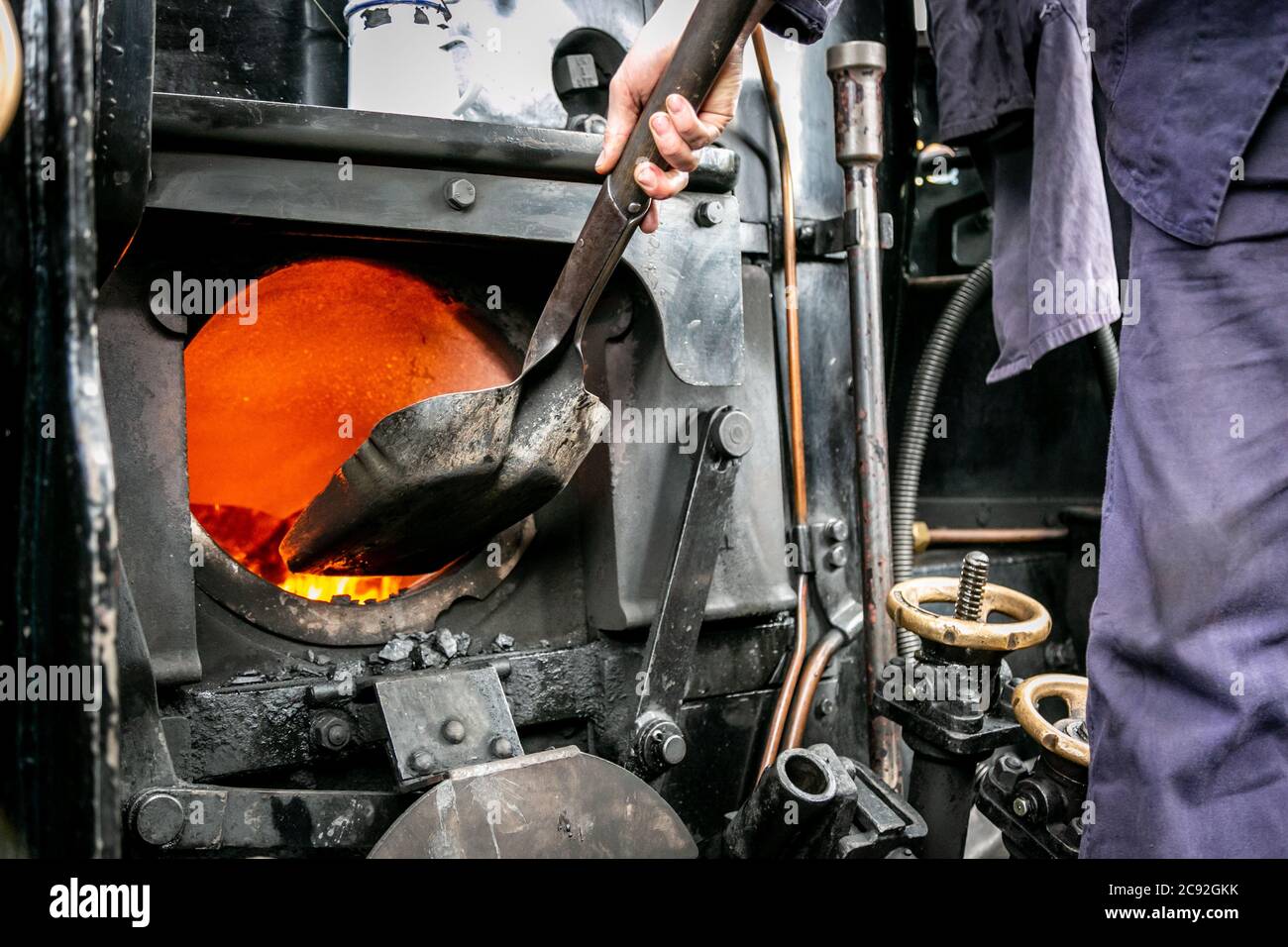 Train driver or fireman putting coal into a steam engine, UK Stock Photo