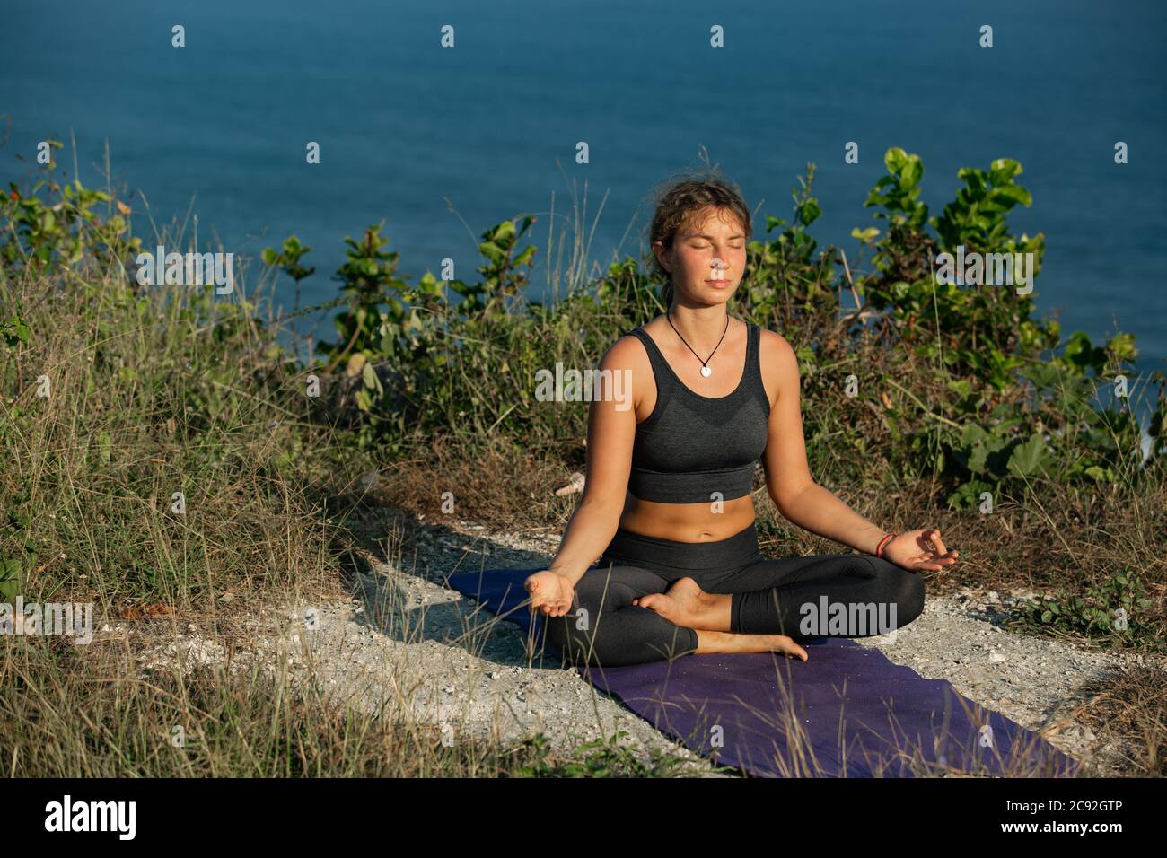 Young woman doing yoga outdoors with amazing back view. Bali. Indonesia. Stock Photo