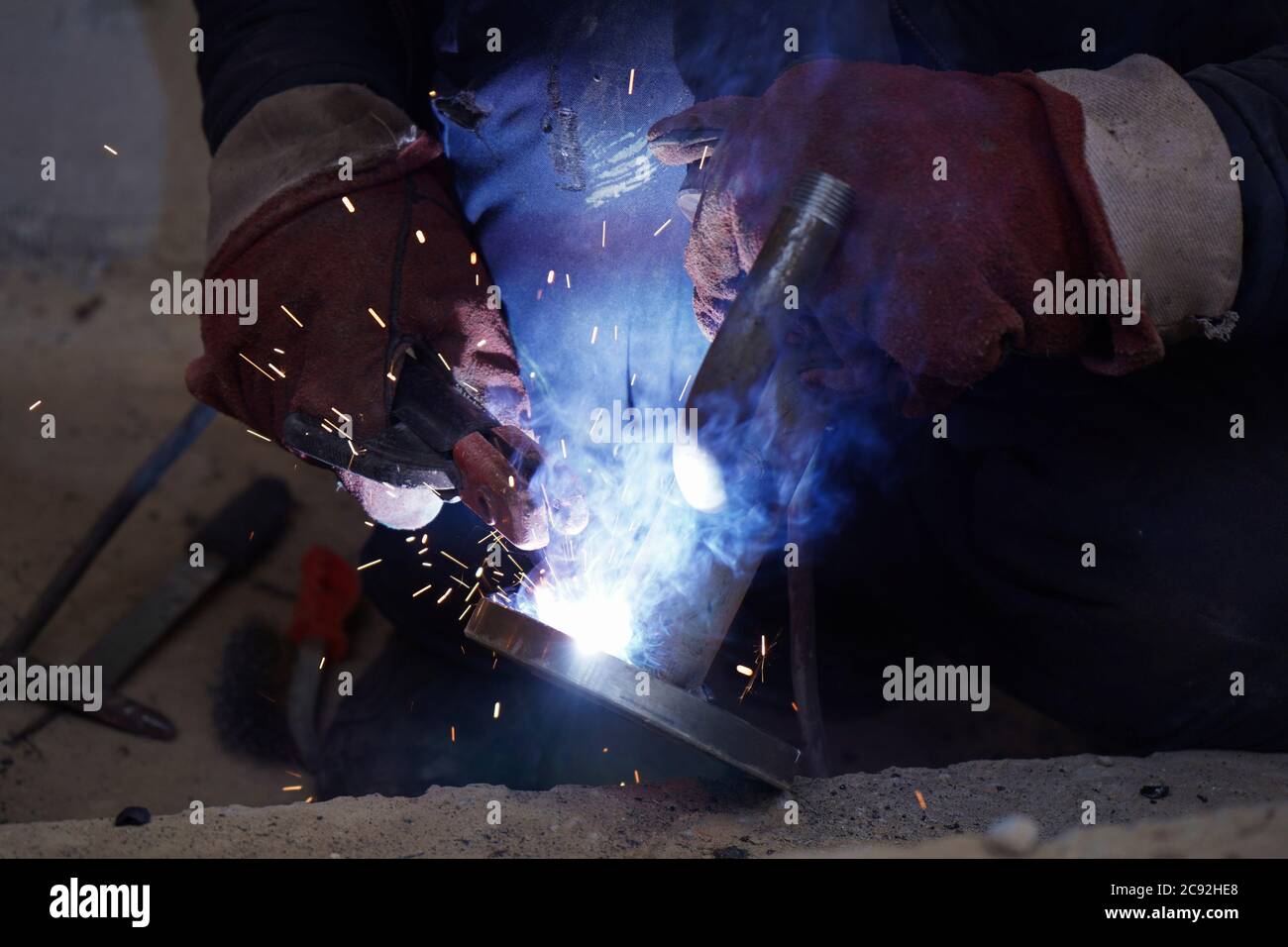 Close-up welder working with electrode at semi-automatic arc welding in manufacture production plant.Bright sparks from welding Stock Photo