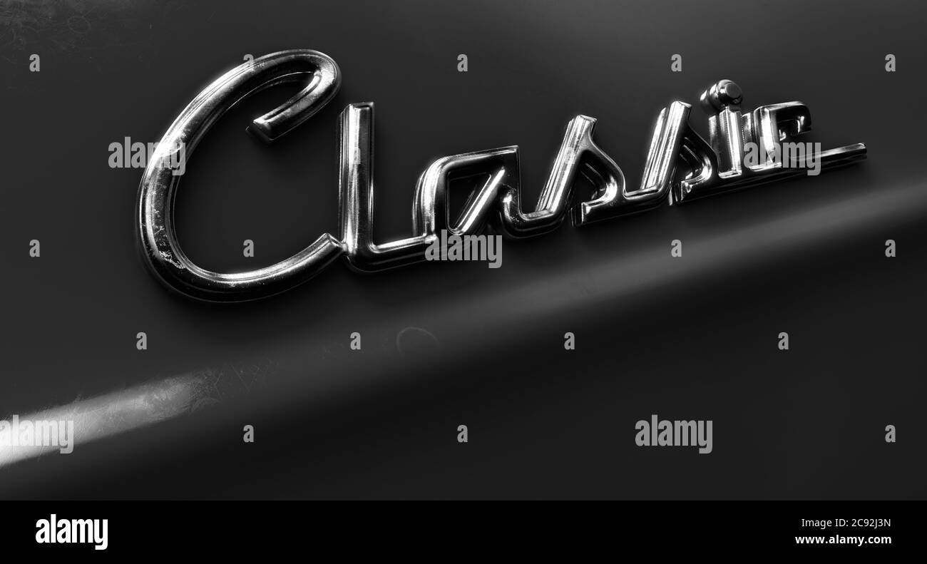 A closeup view of the word classic written as a chrome emblem in a retro font set on a car painted in reflective red paint - 3D render Stock Photo