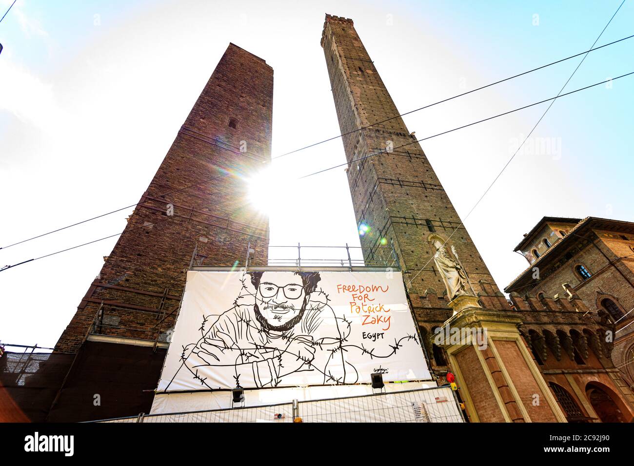 Bologna, Italy. 28th July, 2020. A large billboard installed under the Two Towers carries now Patrick Zaki's face (the picture was conceived by the artist Gianluca Costantini), demanding his freedom from a Egypt Jail on July 28, 2020 in Bologna, Italy. Patrick George Zaki it's a 28 year old Egyptian human rights activist, was abducted at Cairo International Airport upon his arrival from Bologna (Italy) where he currently studies for his MD at the University of Bologna and was tortured and electrocuted without any true accusations. Credit: Massimiliano Donati/Alamy Live News Stock Photo