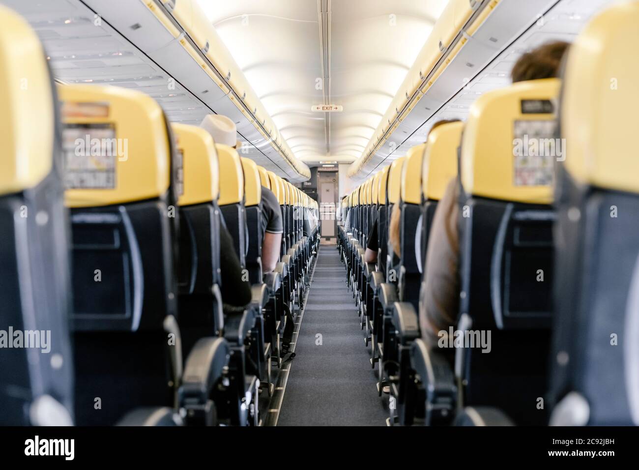 Empty corridor in the airplane with all passengers sitting down. Stock Photo