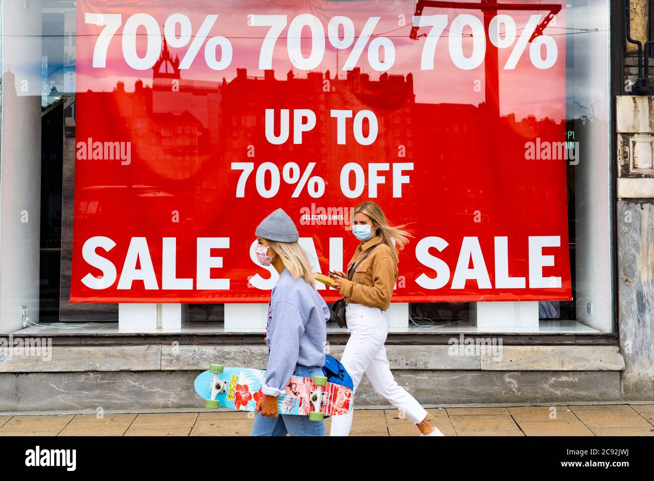 Edinburgh, Scotland, UK. 28 July, 2020. Business and tourism slowly returning to the shops and streets of Edinburgh city centre. Women walk past shop window of Topshop on Princes Street with large sale poster on display. Iain Masterton/Alamy Live News Stock Photo