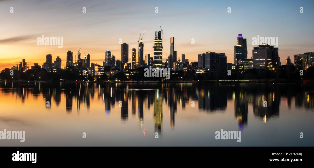 The reflections of the melbourne city skyline at dusk in the still water of albert park lake Stock Photo
