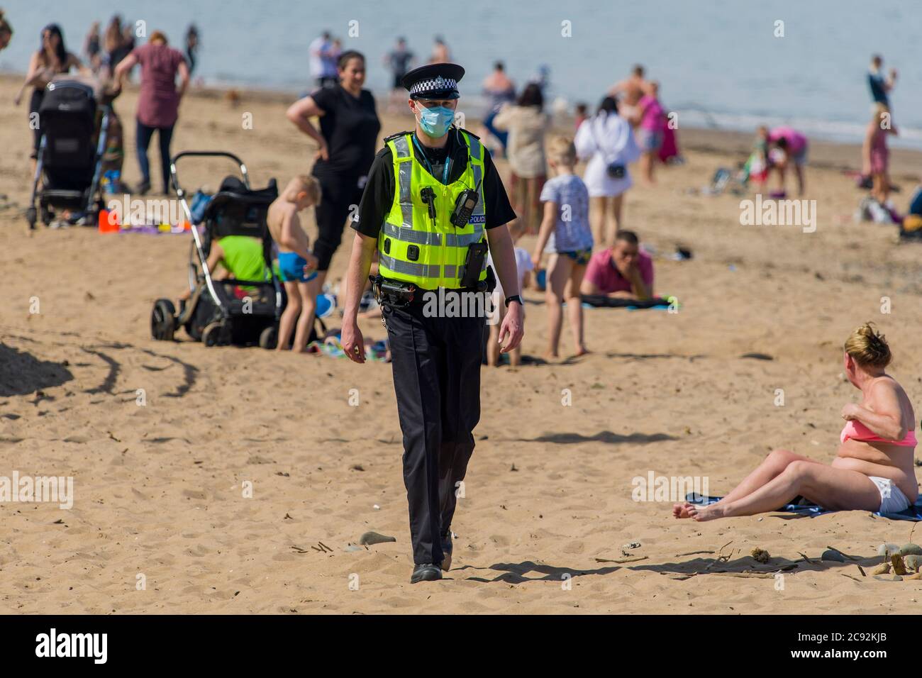 Masked police ask members of the public to leave the sunshine of up to 21 degrees today in Edinburgh's Portobello beach. Scotland is in a 9th week of lockdown due to the covid-19 outbreak.  Credit: Euan Cherry Stock Photo