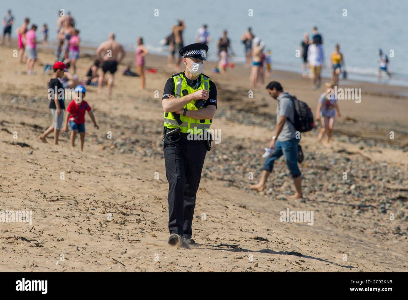 Masked police ask members of the public to leave the sunshine of up to 21 degrees today in Edinburgh's Portobello beach. Scotland is in a 9th week of lockdown due to the covid-19 outbreak.  Credit: Euan Cherry Stock Photo