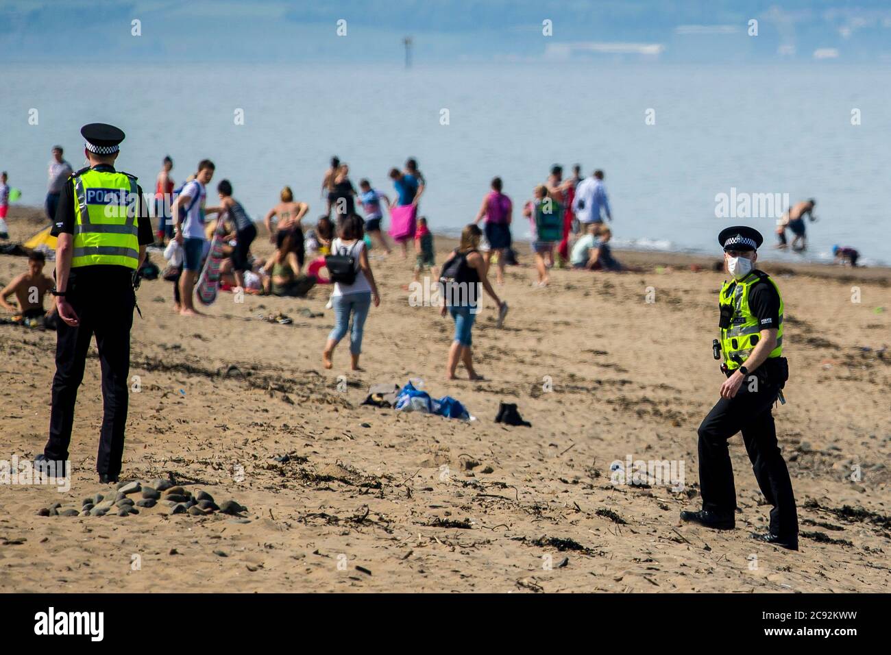 Masked police ask members of the public to leave the sunshine of up to 21 degrees today in Edinburgh's Portobello beach. Scotland is in a 9th week of lockdown due to the covid-19 outbreak.  Credit: Euan Cherry Stock Photo