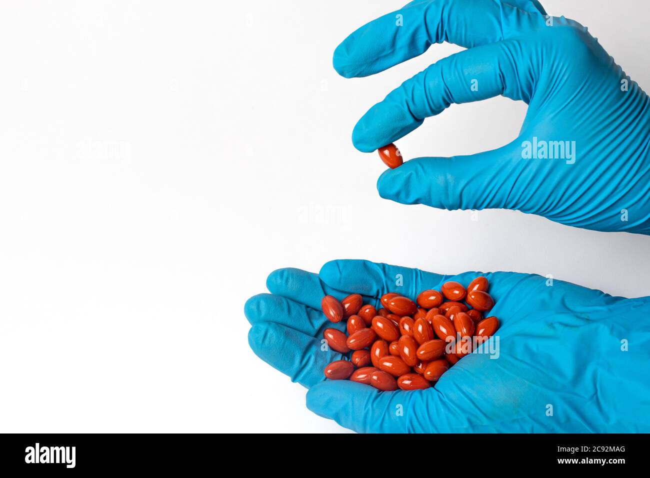 A handful of red lutein tablets in the hands of a man. The benefits of lutein. Stock Photo