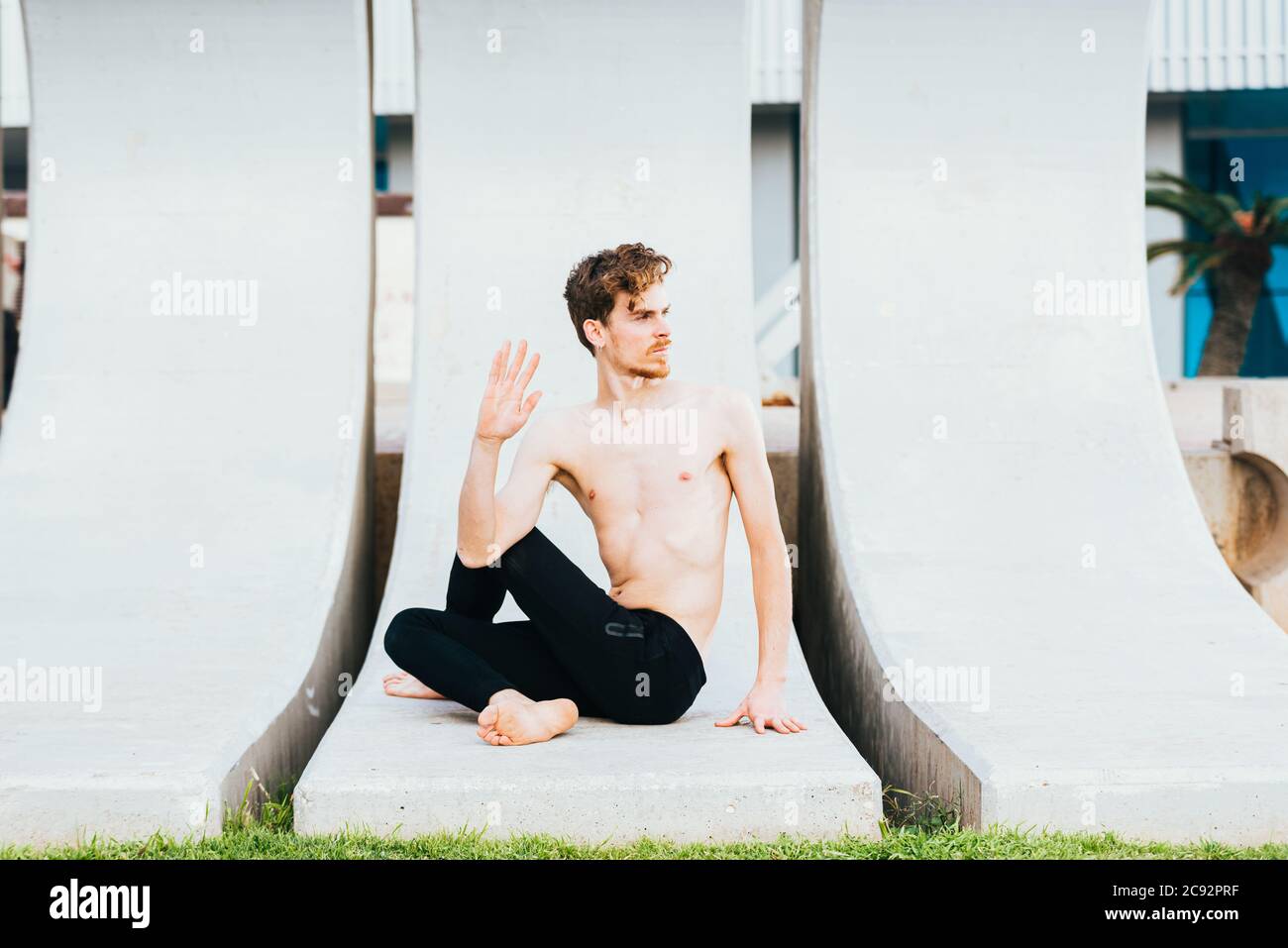 Young man  in the city in the yoga position ardha matsyendrasana stretching and relaxing her body and mind. Stock Photo