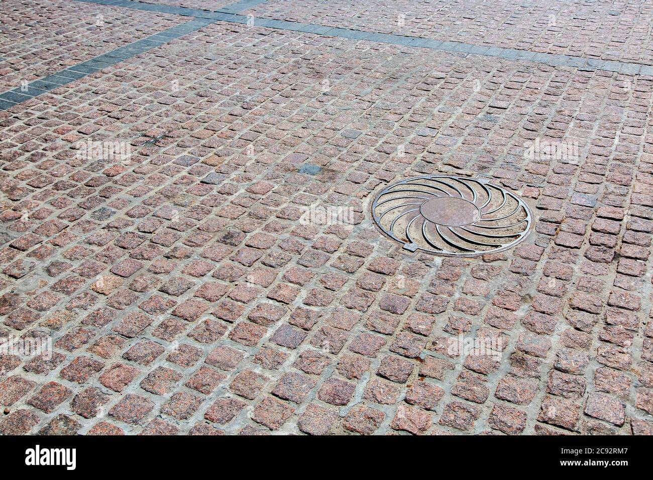 road from a stone blocks, old background texture, iron manhole. Stock Photo