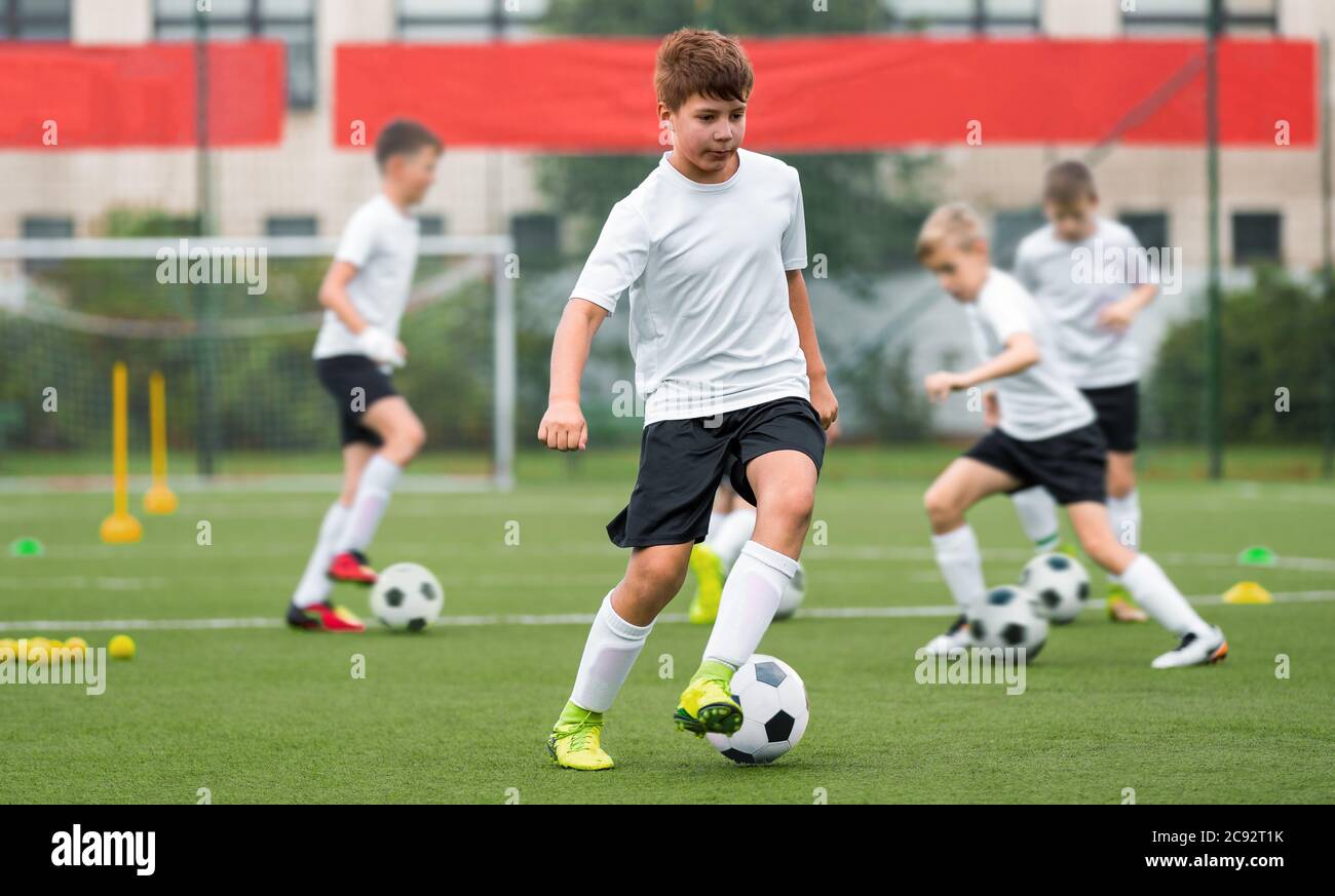 Children kicking soccer balls on artificial grass training field. Young