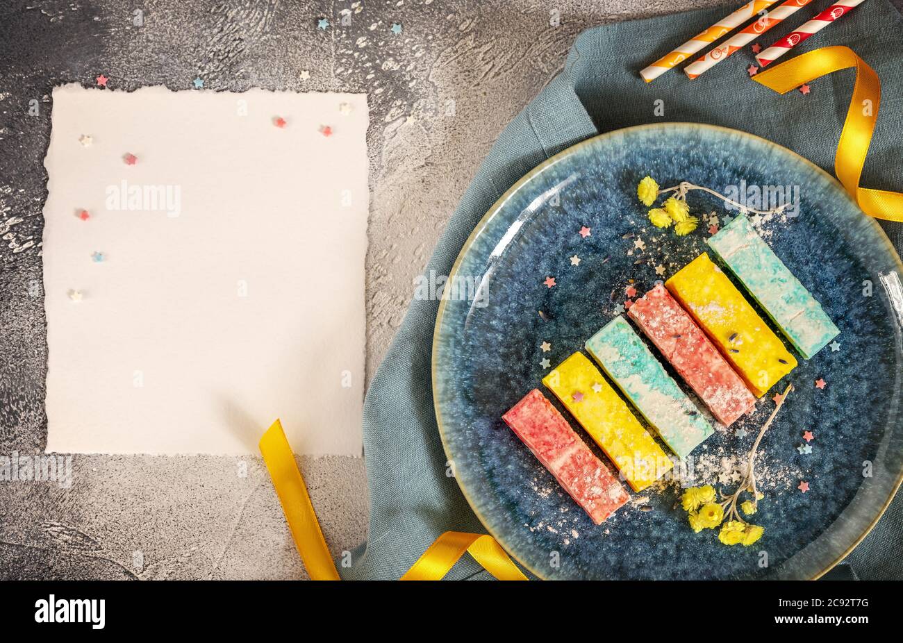 Colorful marshmallows on a blue plate with ribbons, flowers and white sheet Stock Photo