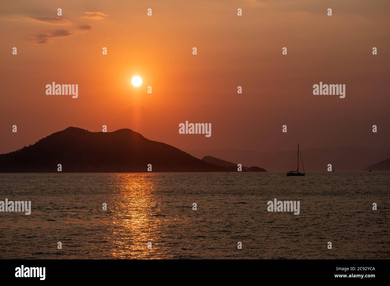 Boat at sea while sun sets Stock Photo - Alamy