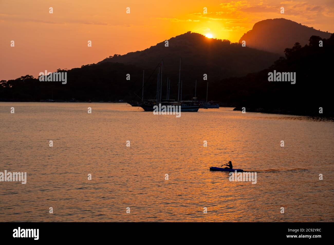 Boat at sea while sun sets Stock Photo - Alamy