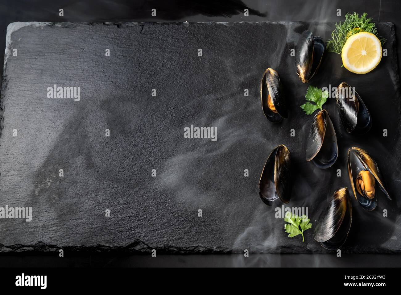 Black mussel with lemon serve on black stone plate. Fresh seafood food and european cuisine gourmet concept. Stock Photo