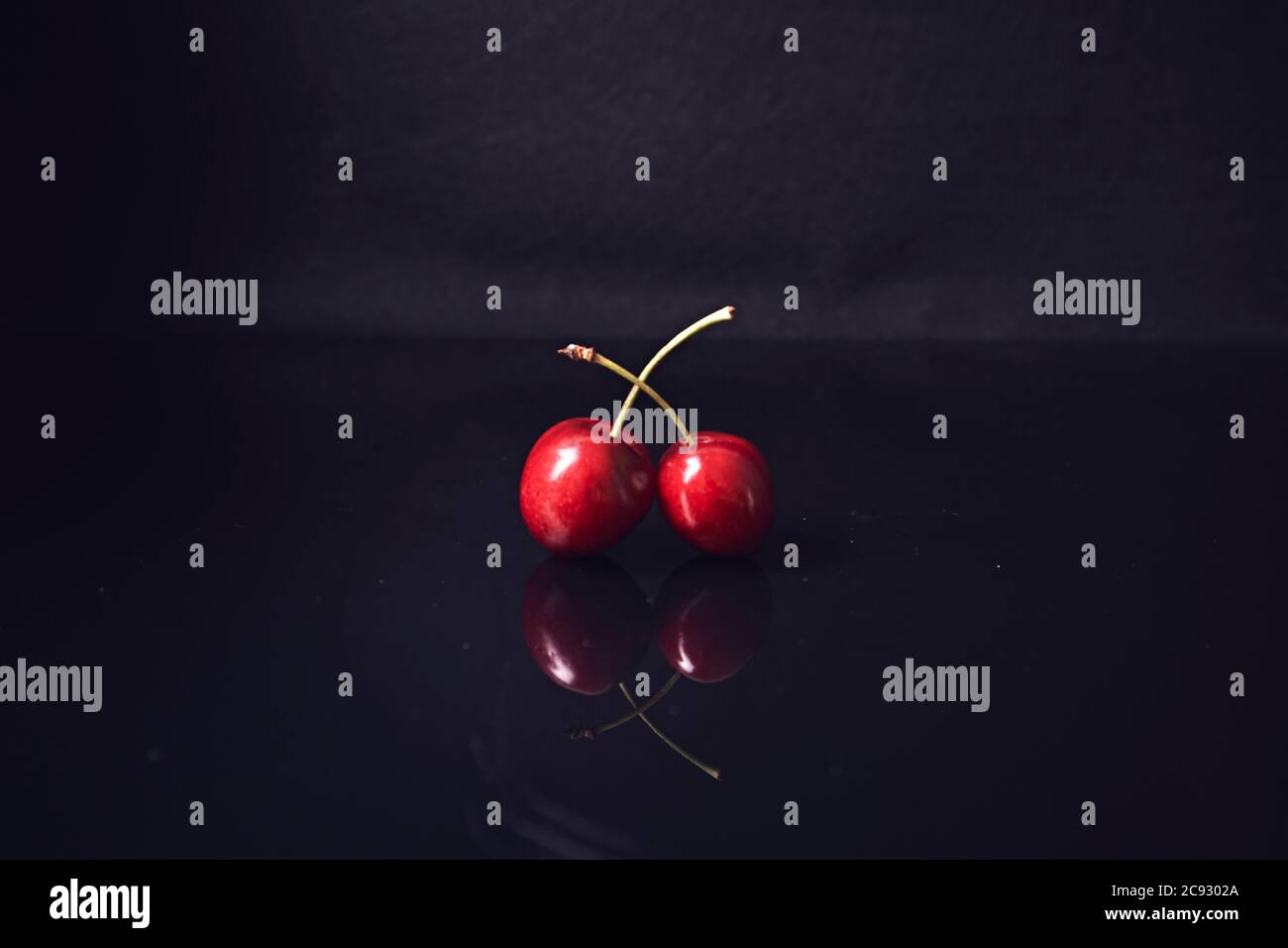 reflection of two cherries on black background Stock Photo