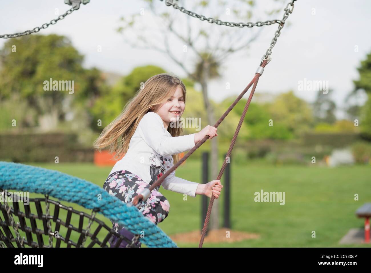 Young girl playing on a swing at a playground Stock Photo - Alamy